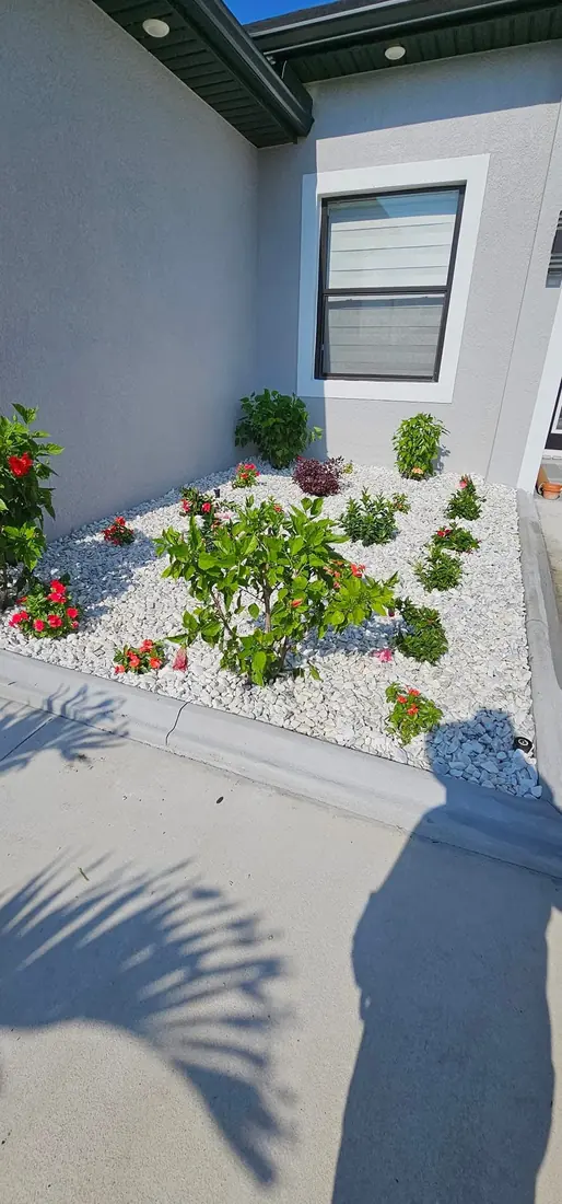 White rock garden bed with flowering plants by RDZ Home Services